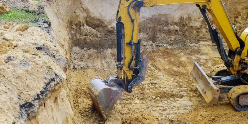 Excavator digging a foundation trench on a groundworks site in Surrey