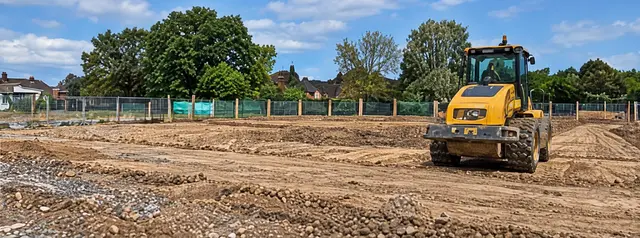 Roller compacting prepared ground on a cleared development site