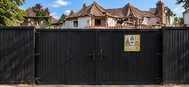 Double vehicle gates set into black timber hoarding